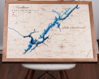 May include: A wooden map of Lake Guntersville in Alabama, with a blue water depth gradient. The map is framed in a natural wood frame. The text "Faulkner Lake House Est. 2013" is in the top left corner. The text "Lake Guntersville Alabama" is in the top right corner. The text "Surface area: 67,900 acres Max. depth: 60 ft" is in the bottom center.