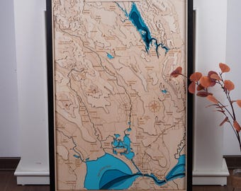 May include: A wooden 3D map of The Napa Valley, California. The map is laser cut and features a blue water detail. The map is framed in black.