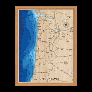 Puede incluir: Un mapa de madera de la costa de Oreg&oacute;n con un relieve 3D azul del oc&eacute;ano. El mapa incluye las principales ciudades, autopistas y bosques nacionales. El texto "OREGON COAST" est&aacute; impreso en la parte inferior del mapa.