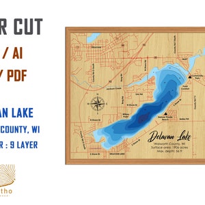 May include: Laser cut map of Delavan Lake in Walworth County, Wisconsin. The map is blue and shows the depth of the lake. The map is surrounded by a wooden frame. The text "Delavan Lake" is written in cursive on the map. The text "Walworth County, WI" is written below the lake name. The text "Surface area: 1906 acres" is written below the county name. The text "Max. depth: 56 ft" is written below the surface area text.