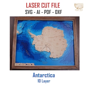 Może przedstawiać: Oprawiona, wielowarstwowa drewniana mapa Antarktydy, przedstawiająca topografię kontynentu i otaczające głębiny oceaniczne w odcieniach niebieskiego i beżowego. Tekst "Antarctica 10 Layer" jest wyświetlany na dole. Rama jest drewniana.