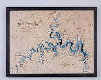 May include: A wooden map of Table Rock Lake in Missouri and Arkansas. The lake is shown in blue, with the surrounding land in brown. The map is framed in black and includes the text "Table Rock Lake", "Missouri - Arkansas", "Surface area: 43,100 acres", and "Max. depth: 220 ft".