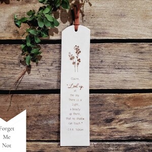 The Forget Me Not flower design.  You can request a name or up to a couple words at the beginning of this note: Look up at the sky.  There is a light, a beauty up there, that no shadow can touch.  -J.R.R. Tolkien.