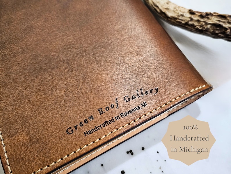 Puede incluir: Un diario de cuero marr&oacute;n con el texto "Green Roof Gallery Handcrafted in Ravenna, MI" grabado en la portada.