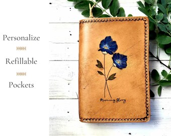 May include: A tan leather journal cover with a floral design featuring two blue morning glory flowers. The cover has a stitched border and the text "Morning Glory" is embossed on the bottom.