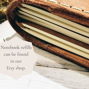 Puede incluir: Primer plano de un cuaderno encuadernado en cuero marr&oacute;n con costuras visibles. El cuaderno est&aacute; abierto, revelando p&aacute;ginas de color crema. El texto en la imagen dice: "Las recargas de cuaderno se pueden encontrar en nuestra tienda Etsy."