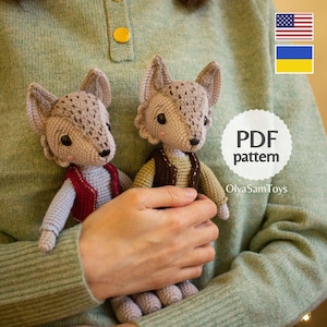 Puede incluir: Dos muñecos de lobo de ganchillo con pelaje gris y detalles. Uno lleva un chaleco rojo, el otro un chaleco marrón. Los muñecos se sostienen frente a una persona que lleva un suéter verde. Un círculo blanco con "PDF pattern" es visible.