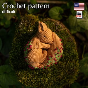 Peut inclure: Patron de crochet pour un amigurumi de renard endormi. Le renard est enroulé sur lui-même avec sa queue enroulée autour de son corps. Le renard est brun avec des détails de broderie verts et rouges. Le patron est qualifié de "difficile".