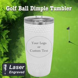May include: White stainless steel tumbler with a golf ball dimpled design. The tumbler has a round area for a custom logo or text. The text "Your Logo or Custom Text" is printed on the tumbler. The tumbler is laser engraved.