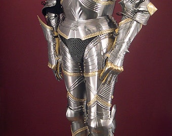 May include: A full suit of silver and gold plated armor with a helmet, gauntlets, and pointed shoes. The armor is displayed on a wooden base.