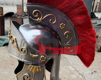 May include: A silver Roman helmet with gold accents and a red horsehair crest. The helmet has a decorative design on the front and sides.