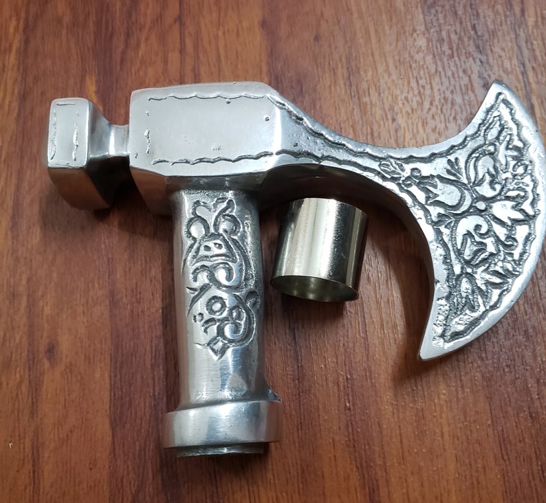 Puede incluir: Un bast&oacute;n de paseo de metal plateado en forma de hacha con un dise&ntilde;o ornamentado y una tapa de metal plateado en el mango.