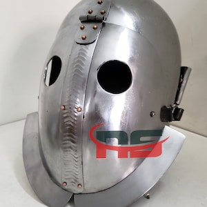Puede incluir: Un casco plateado con una máscara facial y una visera con bisagras. El casco tiene una superficie texturizada y está decorado con remaches y una bisagra.