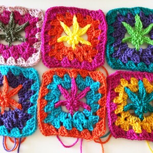 May include: Six colourful crocheted squares with a leaf design in the centre. The squares are in shades of pink, orange, yellow, green, blue, and purple.