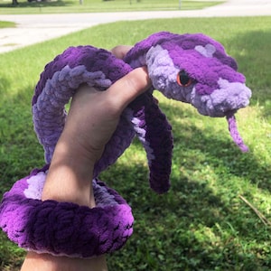 May include: A purple and lavender crocheted snake plush toy with orange eyes.