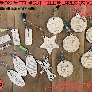 May include: A collection of 12 wooden keychains with inspirational quotes and religious themes. The keychains are made of light brown wood and feature various designs, including stars, doves, and angels. The keychains are strung together with silver chains and have colourful tassels.