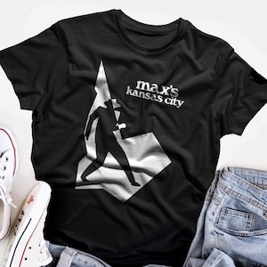 May include: Black t-shirt with a white silhouette of a person walking and the text "max's kansas city" in white.