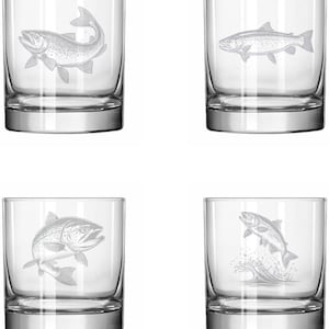 May include: Four clear, lowball glasses with etched fish designs. Each glass features a different depiction of a fish, including one jumping out of water. The glasses have a classic, rounded shape and a thick base.