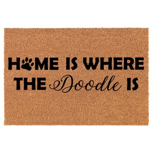 May include: A brown coir doormat with the text "HOME IS WHERE THE Doodle IS" in black lettering. A paw print is included in the word "HOME".