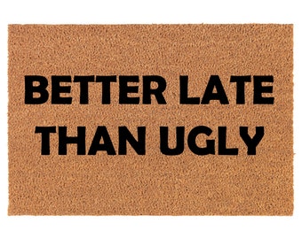 May include: A brown coir doormat with the text "Better Late Than Ugly" in black lettering.