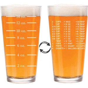 May include: A clear glass measuring cup with a handle, filled with a yellow liquid. The cup has markings for ounces, cups, tablespoons, teaspoons, pints, quarts, and gallons. The front of the cup has the words "FRONT" and "BACK" printed on it.