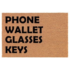 May include: A brown coir doormat with the words "PHONE WALLET GLASSES KEYS" in black lettering.