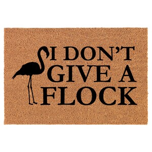 May include: A brown coir doormat with the text "I don't give a flock" in black lettering. A black silhouette of a flamingo is to the left of the text.