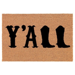 Op de afbeelding: Een bruine kokosvezel deurmat met de tekst "Y'ALL" in zwarte letters en twee zwarte cowboy laarzen silhouetten.