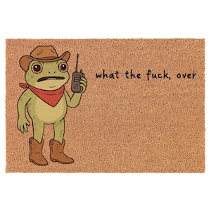 Op de afbeelding: Een deurmat met een cartoonkikker met een cowboyhoed, rode bandana en laarzen, die een walkietalkie vasthoudt. De tekst "what the fuck, over" staat op het bruine oppervlak.