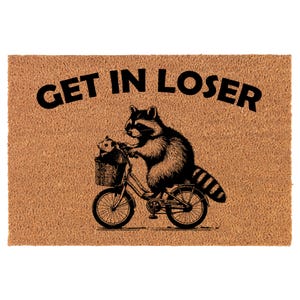 May include: A brown coir doormat with the text "GET IN LOSER" in black lettering. A black and white illustration of a raccoon riding a bicycle with a smaller raccoon in the basket.