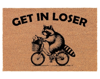 May include: A brown coir doormat with the text "GET IN LOSER" in black lettering. A black and white illustration of a raccoon riding a bicycle with a smaller raccoon in the basket.