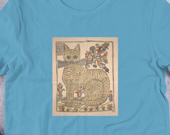 May include: A light blue t-shirt with a vintage illustration of a cat printed on the front. The cat is brown and white with a detailed pattern. The illustration is surrounded by a beige border.