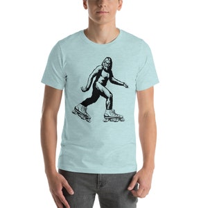 May include: A light blue t-shirt with a black and white illustration of a Bigfoot wearing roller skates.