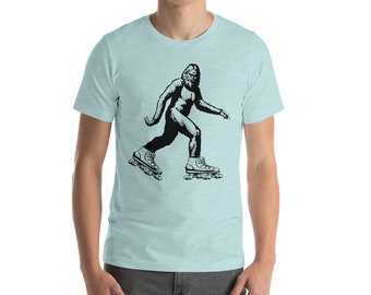 May include: A light blue t-shirt with a black and white illustration of a Bigfoot wearing roller skates.