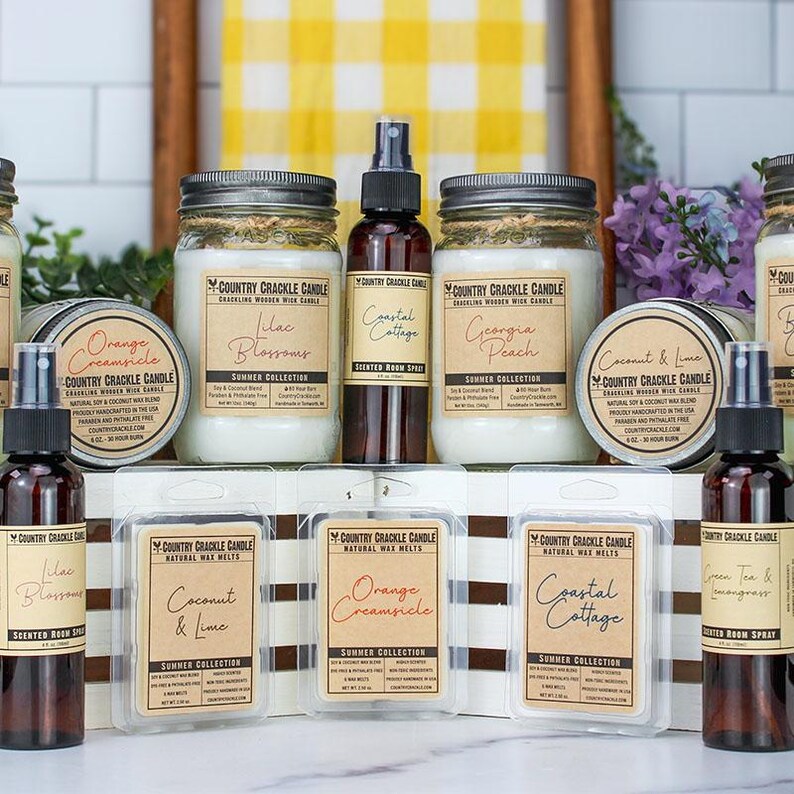 Pode incluir: Uma cole&ccedil;&atilde;o de velas e sprays de ambiente em frascos e garrafas de vidro. As velas s&atilde;o etiquetadas com aromas como Laranja Creamsicle, Flores de Lil&aacute;s, Casa de Praia, P&ecirc;ssego da Ge&oacute;rgia e Coco e Lima. Os sprays de ambiente s&atilde;o etiquetados com aromas como Flores de Lil&aacute;s, Casa de Praia, Ch&aacute; Verde e Erva-Cidreira. Os produtos est&atilde;o dispostos sobre uma superf&iacute;cie branca com um fundo listrado marrom e branco.