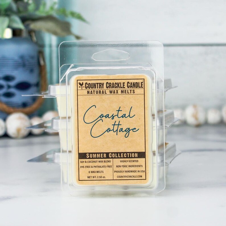 Pode incluir: Um pacote de seis pastilhas de cera de soja e coco em um recipiente de pl&aacute;stico transparente. O r&oacute;tulo diz "Country Crackle Candle Natural Wax Melts" e apresenta o texto "Coastal Cottage" em uma fonte azul de escrita cursiva. O r&oacute;tulo tamb&eacute;m indica "Summer Collection", "Highly-Scented", "Non-Toxic Ingredients", e "Proudly Handmade in USA".