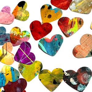 May include: A collection of colorful, heart-shaped wooden ornaments with various abstract painted designs. The hearts feature a range of colors including red, blue, yellow, and pink, with visible brushstrokes and textures. Some hearts have a hole at the top for hanging.