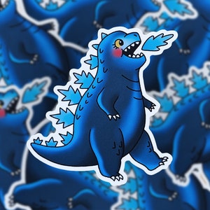 May include: Blue and white sticker of a cartoon Godzilla-like monster breathing fire. The monster is blue with white spikes and a white mouth.
