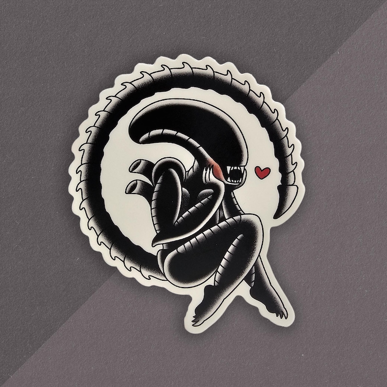 Peut inclure: Autocollant noir et blanc repr&eacute;sentant un extraterrestre dans une pose assise, avec sa queue enroul&eacute;e autour de lui. Un petit c&oelig;ur rouge est &agrave; c&ocirc;t&eacute; de la t&ecirc;te de la cr&eacute;ature. L'autocollant a une bordure blanche avec un bord festonn&eacute;.