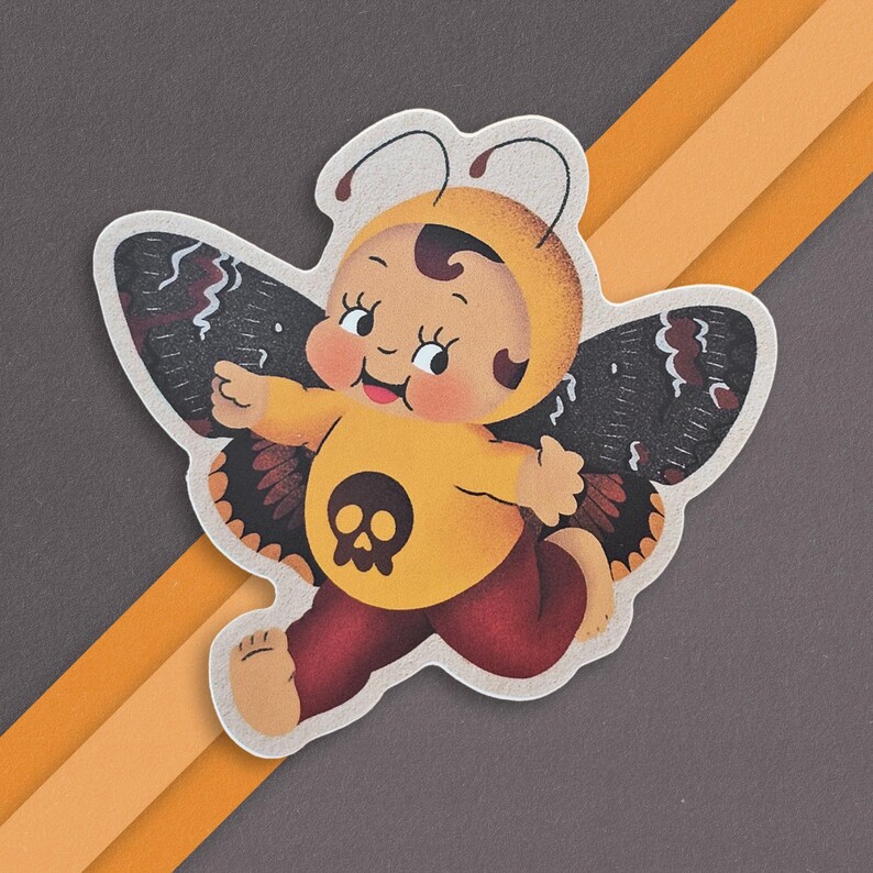 May include: A yellow and black butterfly sticker with a skull design. The butterfly has a human-like face with a big smile.