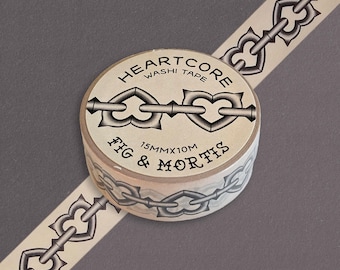 Könnte beinhalten: Eine Rolle beiges Washi-Tape mit einem sich wiederholenden schwarzen Kettenmuster aus herzförmigen Gliedern. Das Etikett zeigt HEARTCORE WASHI TAPE, FIG & MORTIS und 15MMX10M. Das Band ist diagonal abgerollt und zeigt das Ketten-Design.