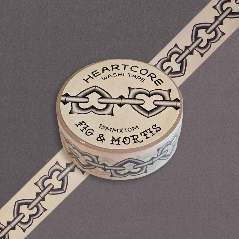 May include: A roll of beige washi tape featuring a repeating black chain pattern with heart-shaped links. The label reads HEARTCORE WASHI TAPE, FIG & MORTIS, and 15MMX10M. The tape is unrolled diagonally across the frame, displaying the chain design.