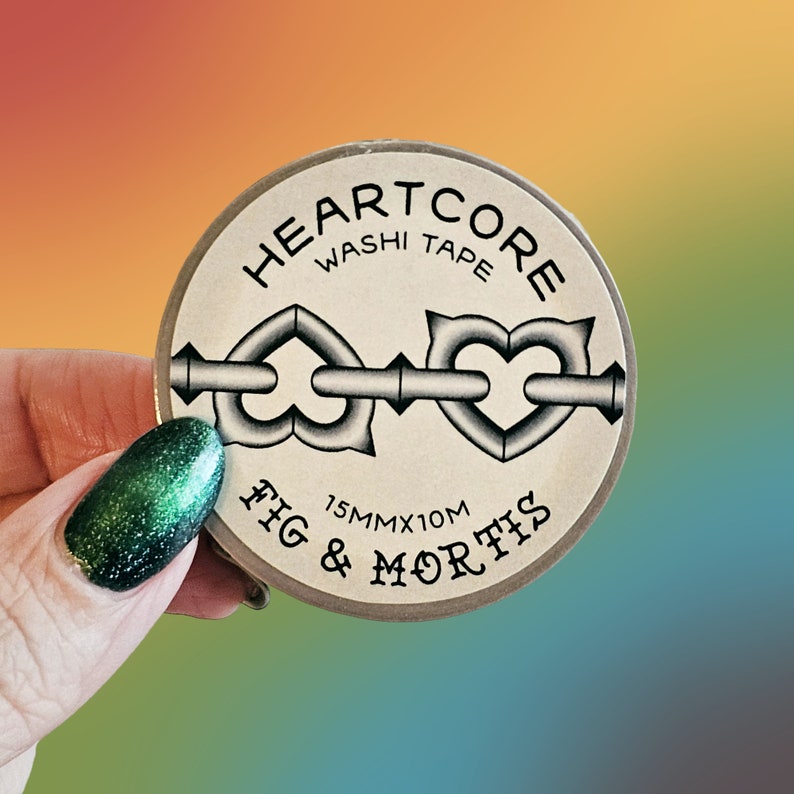 May include: A circular roll of washi tape with a beige label featuring the text HEARTCORE WASHI TAPE and FIG & MORTIS. The label displays a graphic of two heart-shaped links connected by a metal bar and includes the text 15MMX10M.