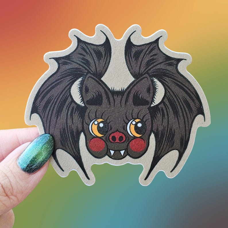 May include: A brown bat with large, round eyes and a toothy grin. The bat has red cheeks and is depicted with black wings.