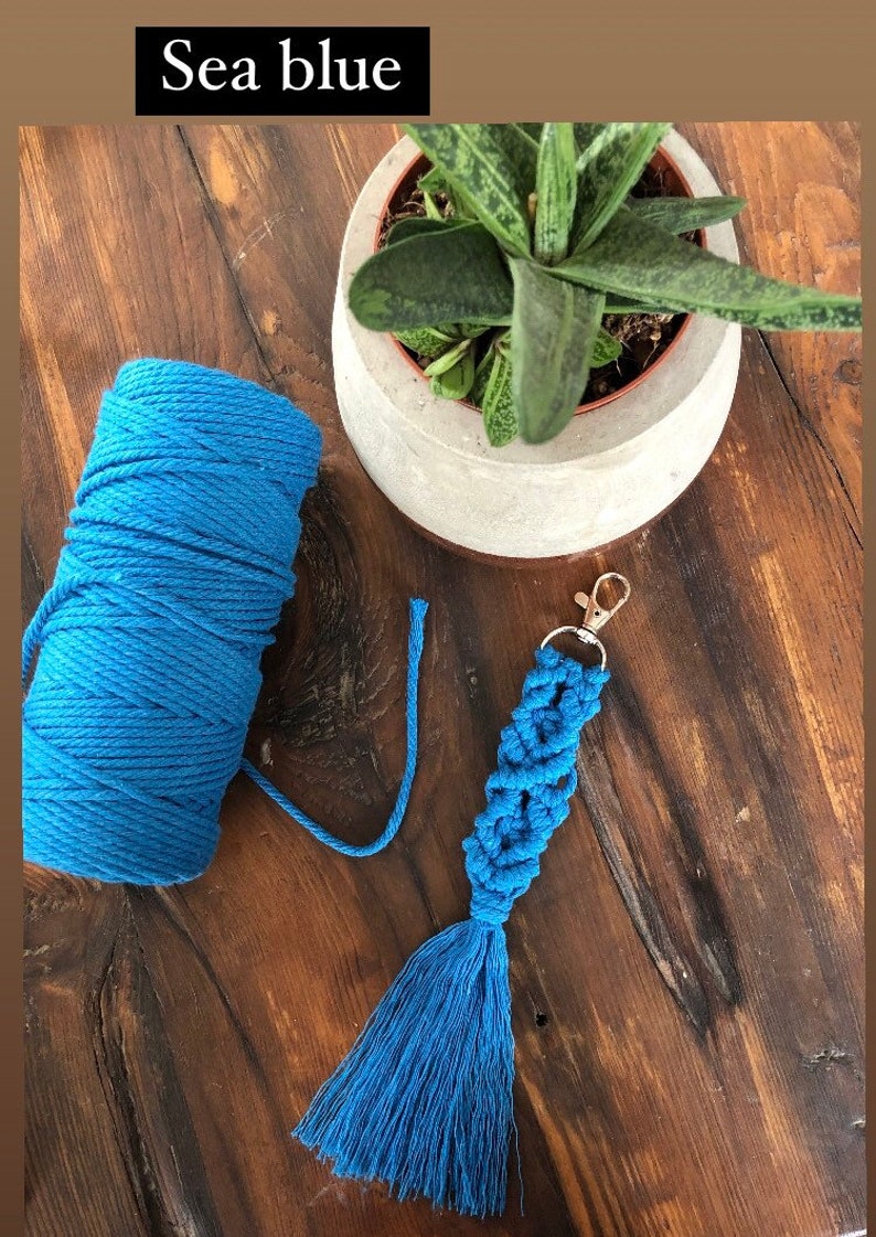 May include: Sea blue macrame keychain with a tassel. The keychain is made with a thick blue cord and has a silver key ring.