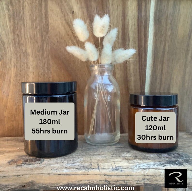 Pode incluir: Dois frascos de velas sobre uma superf&iacute;cie de madeira. O frasco maior &eacute; preto e diz "Medium Jar 180ml 55hrs burn". O frasco menor &eacute; marrom e diz "Cute Jar 120ml 30hrs burn".