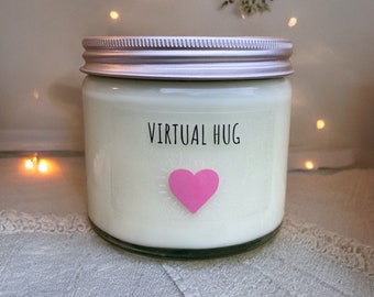 May include: A white candle in a glass jar with a silver lid. The jar has a pink heart with a white outline and the text "VIRTUAL HUG" printed on the front.