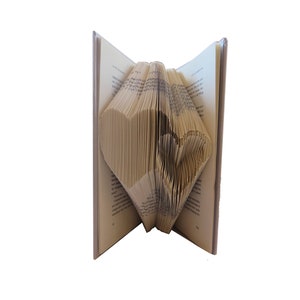 May include: A book with pages folded into the shape of a heart. The book is open and the heart is visible in the center of the book.