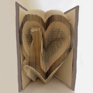 May include: A book folded into the shape of a heart. The pages are folded to create a three-dimensional heart shape.
