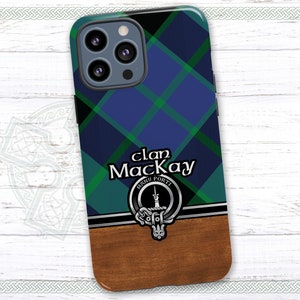 May include: A blue, green, and black plaid phone case with a brown wood accent. The case features a crest with the text "Clan MacKay", "Manu Forti" and a sword.